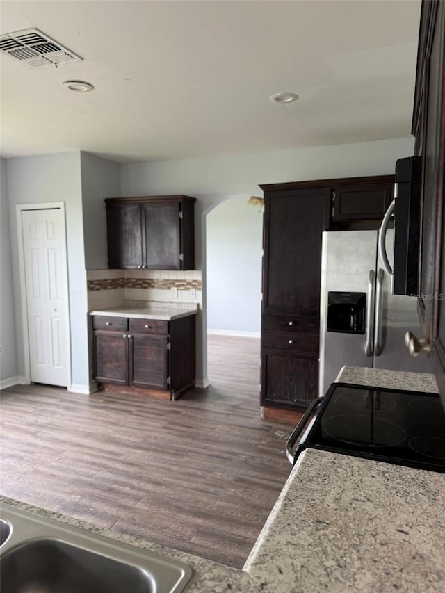 kitchen featuring visible vents, arched walkways, electric range oven, stainless steel fridge with ice dispenser, and dark wood-style flooring