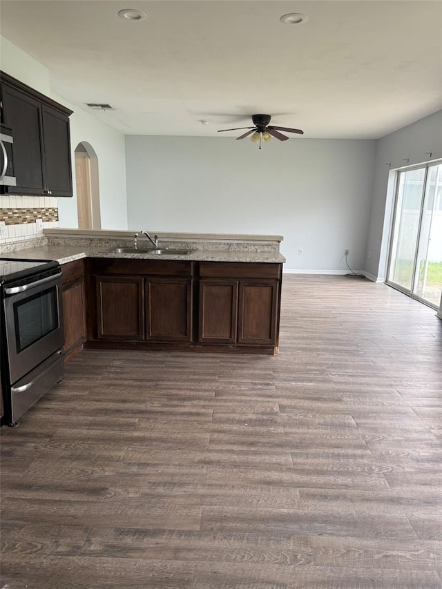 kitchen featuring arched walkways, visible vents, appliances with stainless steel finishes, dark wood-type flooring, and a sink