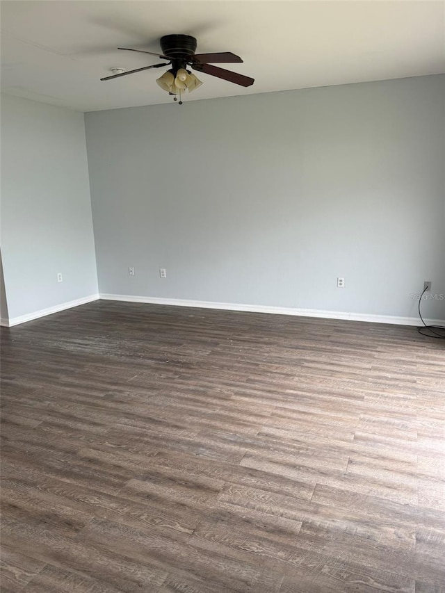 empty room featuring baseboards, dark wood finished floors, and a ceiling fan