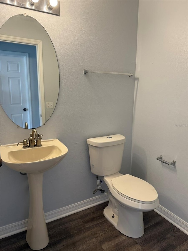 bathroom with baseboards, a sink, toilet, and wood finished floors