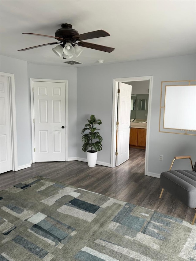 bedroom with a ceiling fan, connected bathroom, baseboards, and wood finished floors