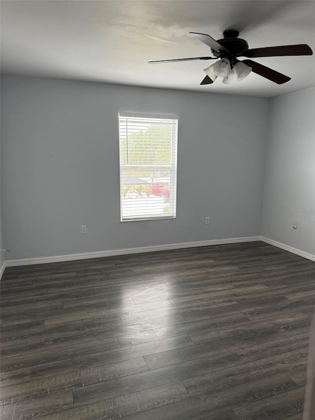 spare room featuring a ceiling fan, baseboards, and dark wood-type flooring