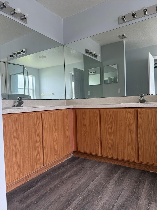 full bath featuring double vanity, visible vents, a sink, and wood finished floors