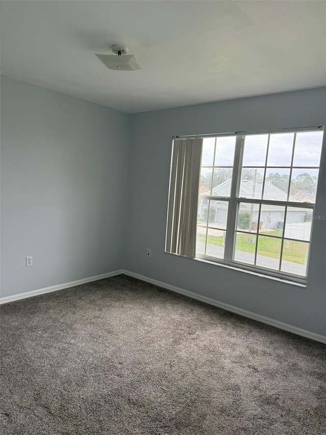 carpeted empty room featuring baseboards