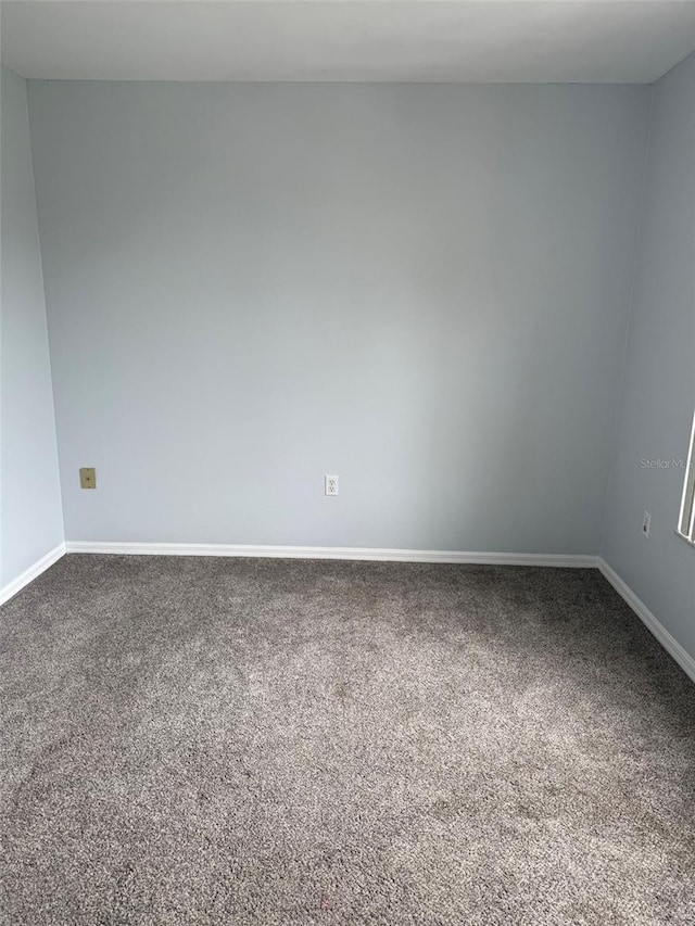 unfurnished room with dark colored carpet and baseboards