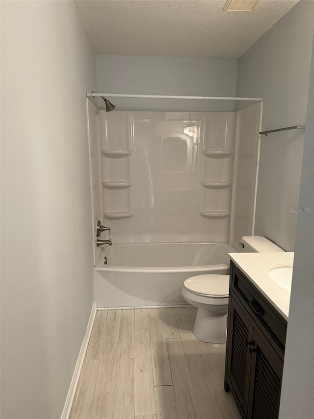 full bath with toilet, tub / shower combination, a textured ceiling, vanity, and wood finished floors