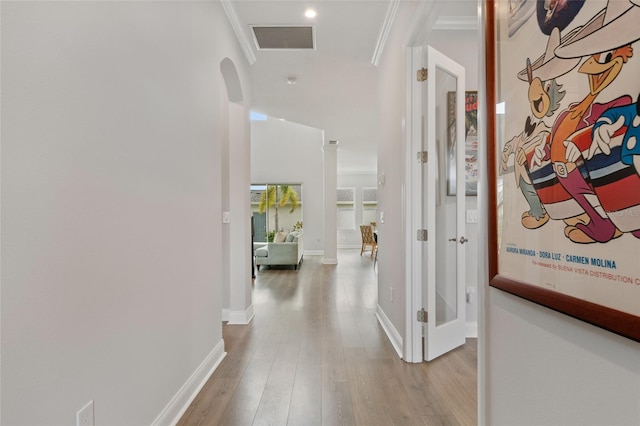 hall featuring ornamental molding, visible vents, baseboards, and wood finished floors