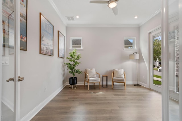 sitting room with baseboards, crown molding, visible vents, and wood finished floors