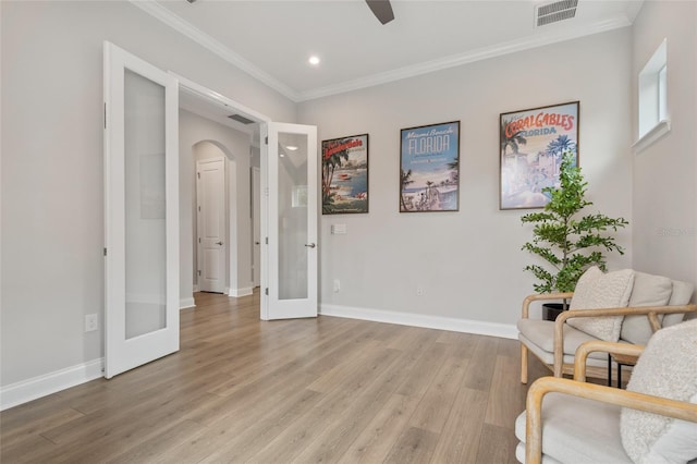 sitting room with light wood finished floors, baseboards, visible vents, ornamental molding, and french doors