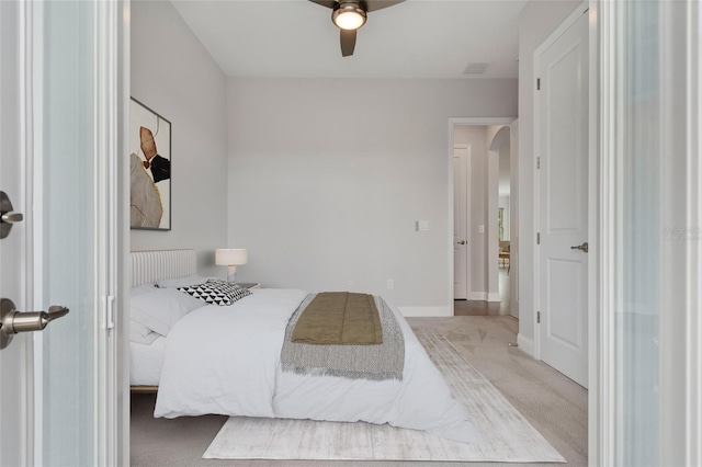 bedroom with arched walkways, light carpet, a ceiling fan, visible vents, and baseboards