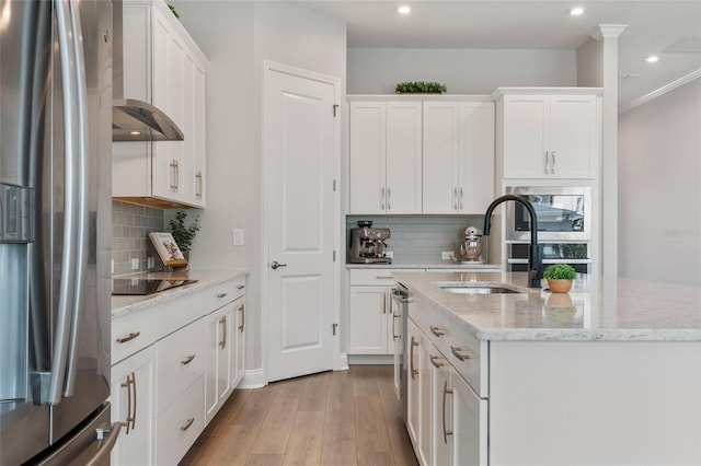 kitchen with white cabinets, a kitchen island with sink, stainless steel appliances, light wood-type flooring, and a sink