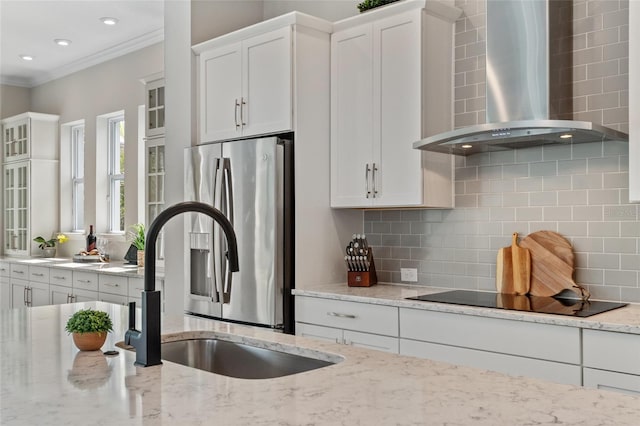 kitchen featuring white cabinetry, stainless steel fridge, wall chimney range hood, and black electric cooktop