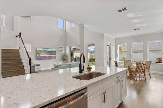 kitchen with light stone countertops, a sink, visible vents, and a healthy amount of sunlight