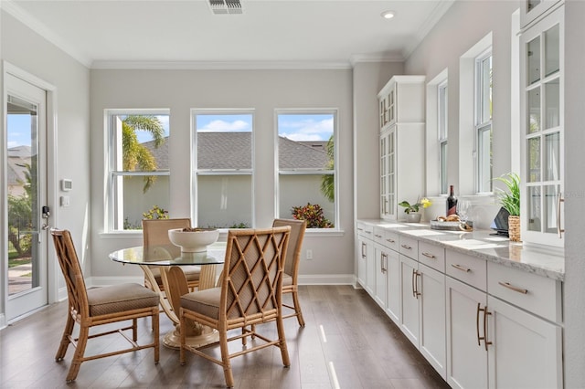 dining space with ornamental molding, visible vents, baseboards, and wood finished floors