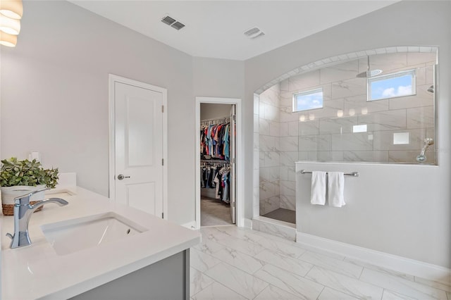 bathroom featuring marble finish floor, visible vents, a sink, and a walk in shower