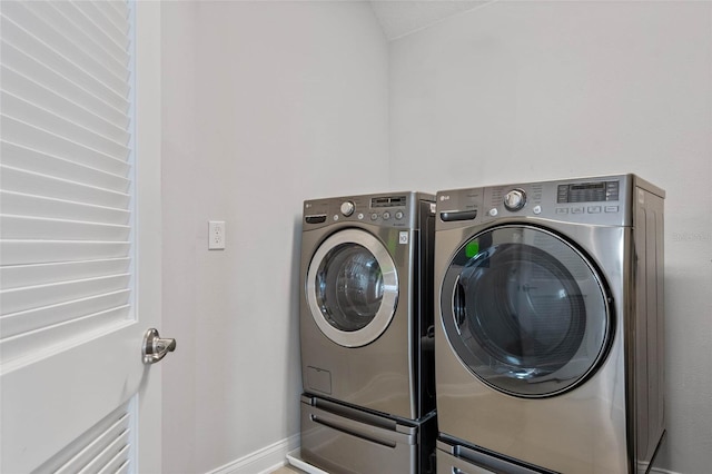 clothes washing area with washer and dryer, laundry area, and baseboards