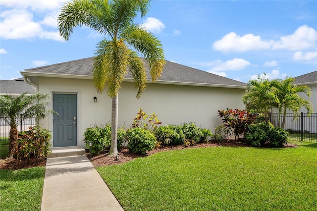 view of front of property featuring stucco siding, a shingled roof, fence, and a front yard