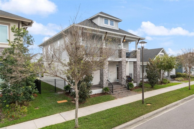 view of front of home with fence, a balcony, a front lawn, and stucco siding