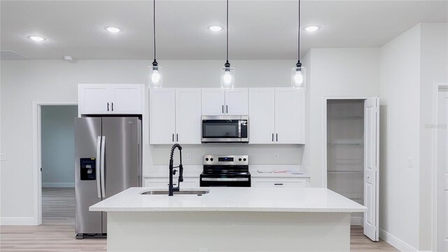 656 Marion Oaks Mnr, Ocala, FL 34473 - kitchen with stainless steel appliances, light wood-type flooring, white cabinetry, a center island with sink, and light countertops
