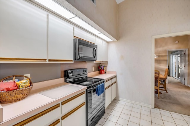 kitchen with white cabinetry, black appliances, and light tile patterned floors