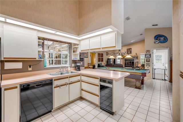 kitchen with light tile patterned floors, sink, black dishwasher, a towering ceiling, and kitchen peninsula