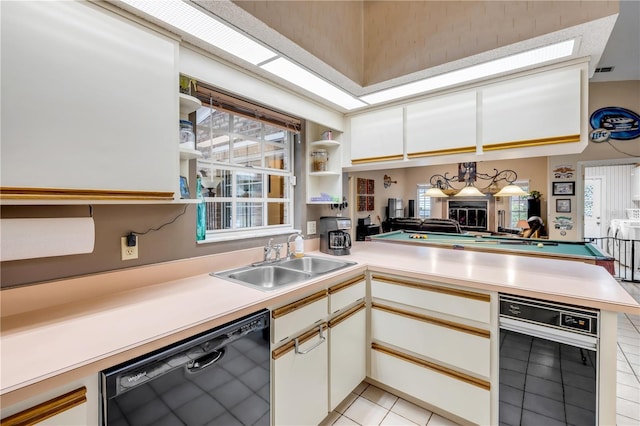 kitchen with kitchen peninsula, sink, dishwasher, light tile patterned floors, and white cabinets