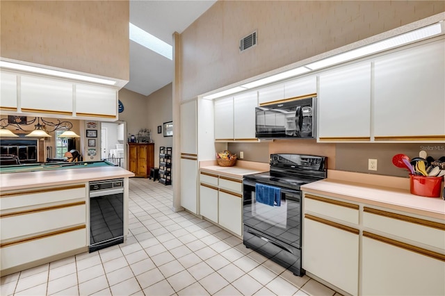 kitchen with light tile patterned flooring, white cabinetry, black appliances, kitchen peninsula, and high vaulted ceiling