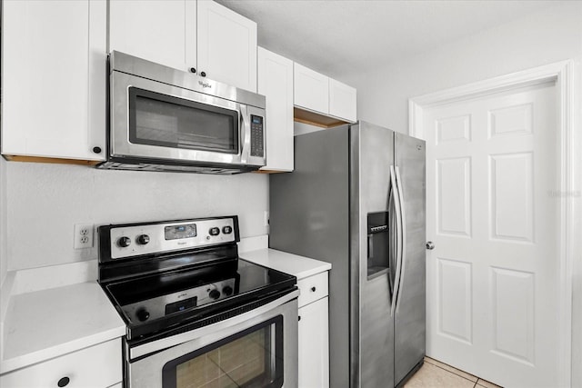 kitchen with light tile patterned floors, stainless steel appliances, light countertops, and white cabinetry