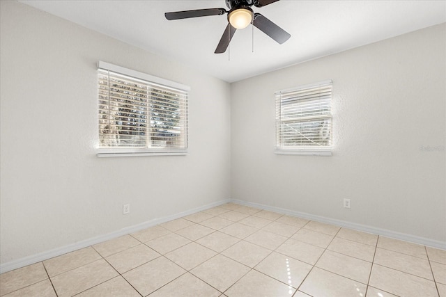 spare room featuring light tile patterned floors, ceiling fan, and baseboards