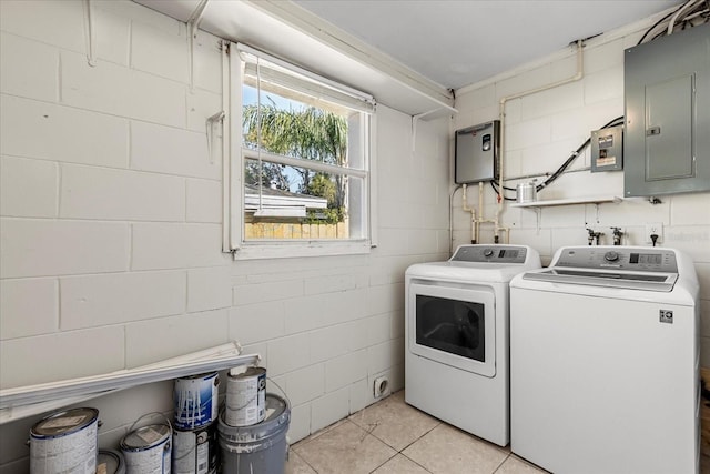 clothes washing area with concrete block wall, light tile patterned floors, washing machine and dryer, laundry area, and electric panel