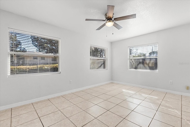 spare room with a ceiling fan, a textured ceiling, baseboards, and light tile patterned floors