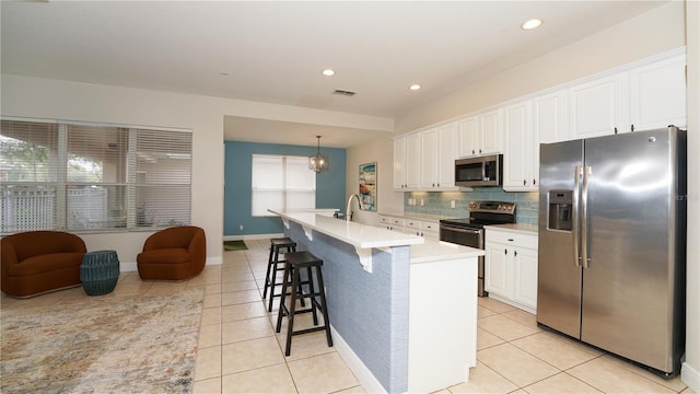 kitchen with light tile patterned floors, white cabinets, stainless steel appliances, and pendant lighting