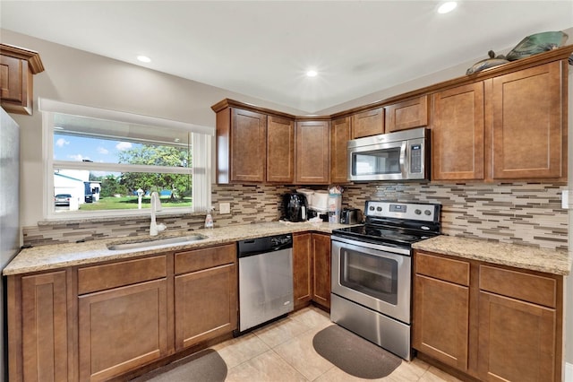 kitchen with sink, appliances with stainless steel finishes, and light stone countertops