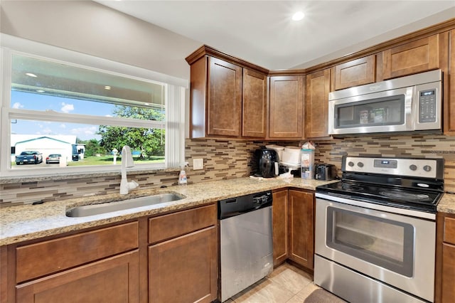 kitchen featuring sink, tasteful backsplash, light stone counters, appliances with stainless steel finishes, and light tile patterned flooring