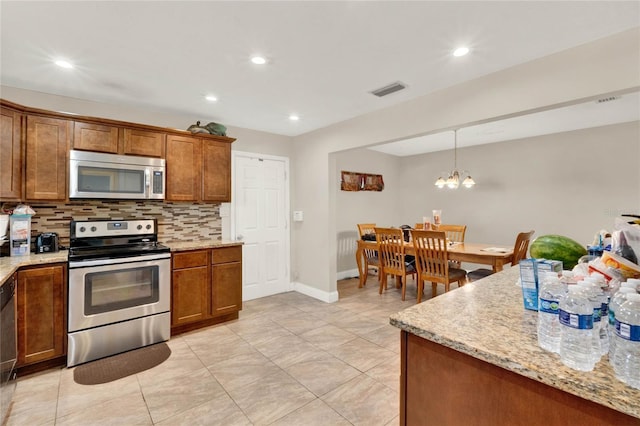 kitchen featuring backsplash, light stone counters, appliances with stainless steel finishes, a chandelier, and pendant lighting