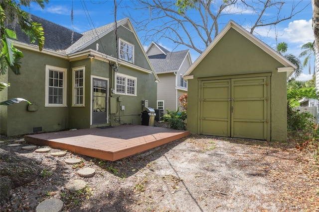 rear view of property featuring a deck, a garage, a shingled roof, crawl space, and stucco siding