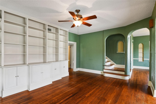 unfurnished room with dark wood-style floors, a textured ceiling, baseboards, and a ceiling fan