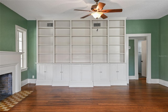 unfurnished living room featuring a textured ceiling, a fireplace, visible vents, a ceiling fan, and dark wood finished floors