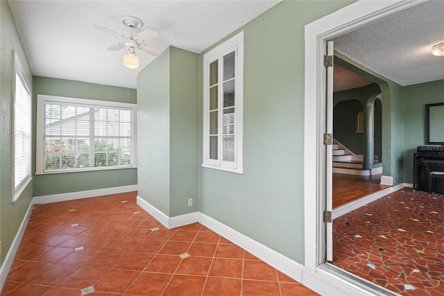 interior space with tile patterned flooring, a textured ceiling, and baseboards