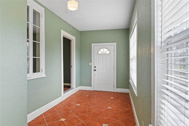 tiled foyer with baseboards and a textured ceiling