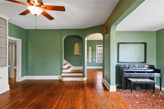 empty room with a textured ceiling, baseboards, and wood finished floors