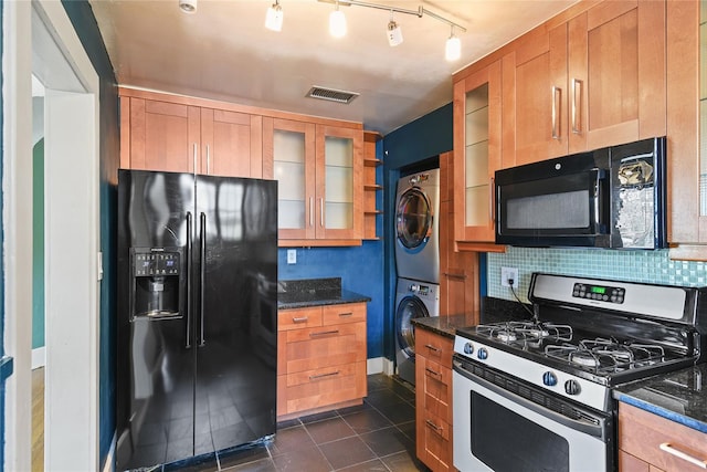 kitchen featuring glass insert cabinets, visible vents, dark stone counters, black appliances, and stacked washer and clothes dryer