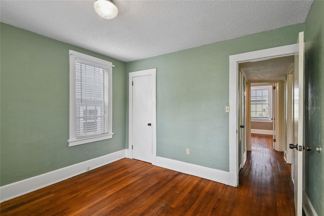 unfurnished bedroom featuring dark wood-style floors, a closet, baseboards, and a textured ceiling