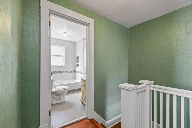 bathroom with a garden tub, baseboards, and a textured wall