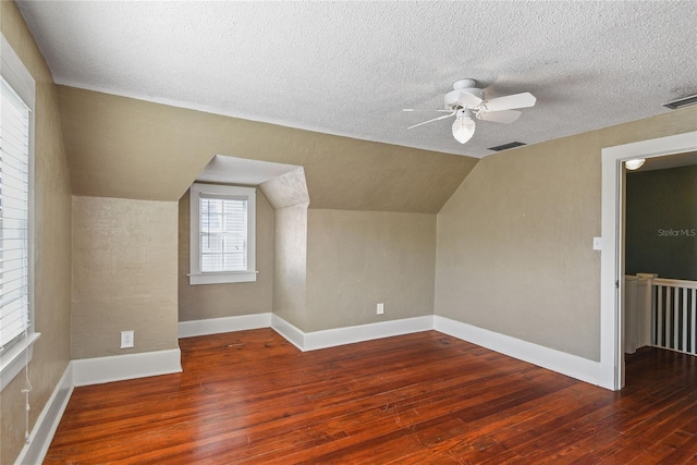 bonus room featuring lofted ceiling, visible vents, dark wood finished floors, and a textured ceiling