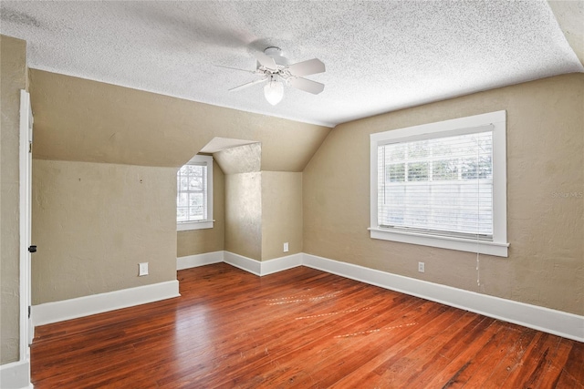 bonus room with ceiling fan, a textured ceiling, wood finished floors, baseboards, and vaulted ceiling