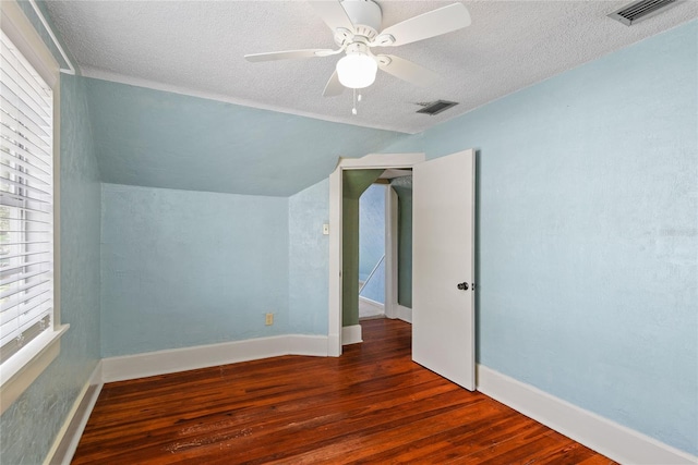 unfurnished bedroom with lofted ceiling, dark wood-style floors, visible vents, and a textured ceiling