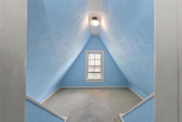 bonus room featuring carpet floors, vaulted ceiling, a textured ceiling, and baseboards