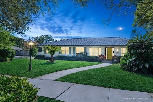 ranch-style home with metal roof, a lawn, and stucco siding