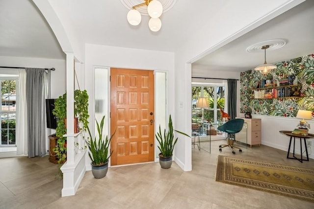 foyer with wallpapered walls and a wainscoted wall